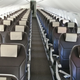 Rows of empty airplane seats on a plane i 2020. The seats are grey with white headrests.